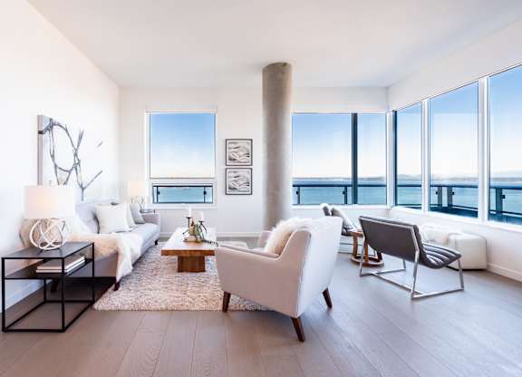 A living room with a white couch, a white chair, and a coffee table.