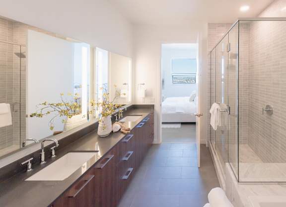 A modern bathroom with a walk-in shower and double sinks.