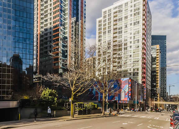 A tall building with a red stripe on the side is in the foreground of a city street.