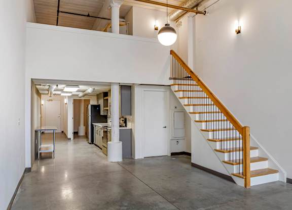 a room with a staircase and a white wall and a ceiling light at Highland Mill Lofts, Charlotte, NC
