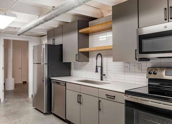 a kitchen with stainless steel appliances and white counter tops at Highland Mill Lofts, North Carolina