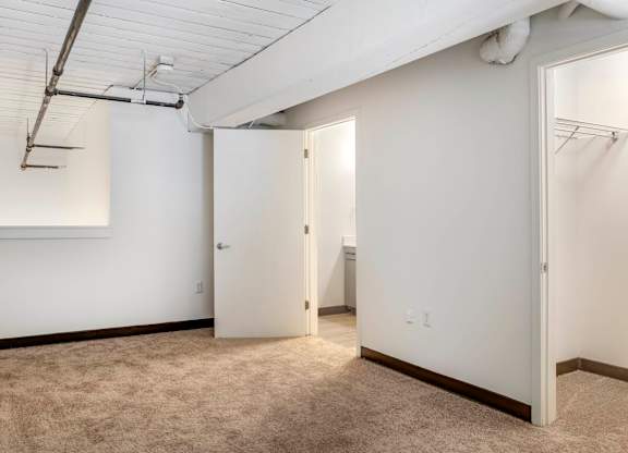 an empty room with white walls and a door to a closet at Highland Mill Lofts, Charlotte, NC
