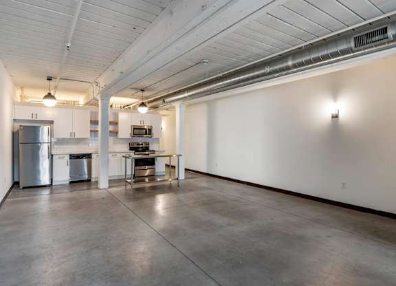 an empty room with a kitchen and a table in the middle at Highland Mill Lofts, Charlotte, North Carolina