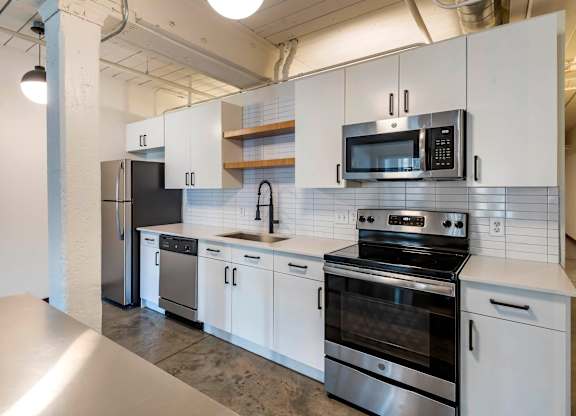 a kitchen with white cabinets and stainless steel appliances at Highland Mill Lofts, Charlotte