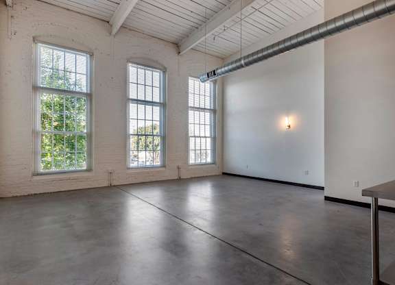 an empty room with three large windows and a table at Highland Mill Lofts, Charlotte, NC
