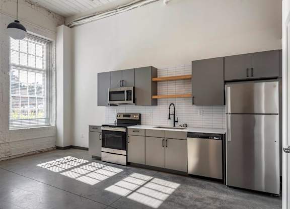 a kitchen with stainless steel appliances and a window at Highland Mill Lofts, Charlotte, North Carolina