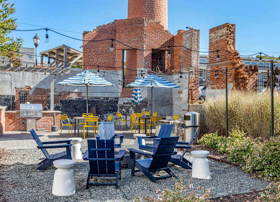 a patio with blue and yellow chairs and umbrellas at Highland Mill Lofts, Charlotte, North Carolina