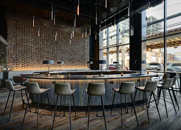 A bar with a brick wall and wooden chairs. at The Mason Apartments, Chicago