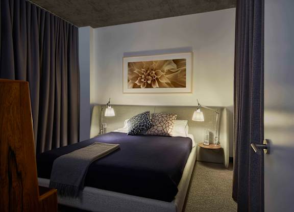 A bedroom with a bed, nightstand, and lamp. at The Mason Apartments, Chicago, Illinois