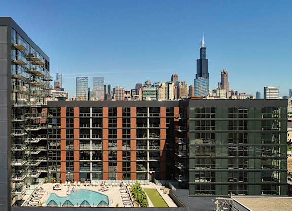A tall building with a red stripe on the side is in the foreground of a city skyline. at The Mason Apartments, Chicago, IL, 60607