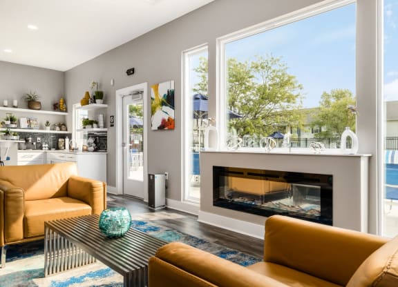 A modern living room with a fireplace and a view of the backyard at Estates at Brentwood Lake Apartments, Reynoldsburg, 43068
