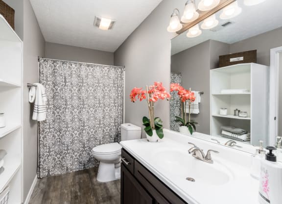 A bathroom with a white sink, toilet, and a shower with a grey and white shower curtain at Estates at Brentwood Lake Apartments, Ohio, 43068