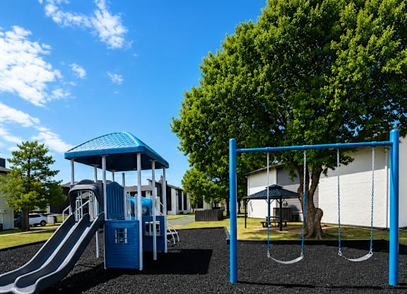 A playground with a blue slide and a blue and white swing set.