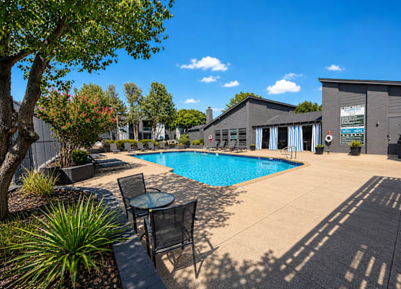 A pool area with a table and chairs.