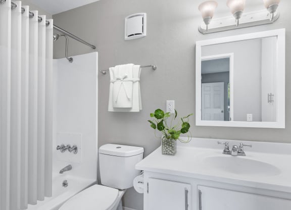 a white bathroom with a mirror and a toilet and a sink