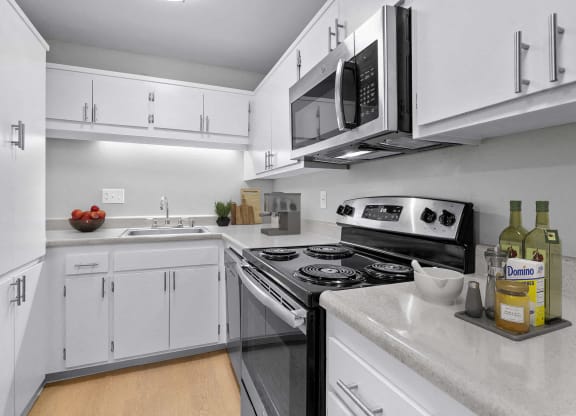 a kitchen with white cabinets and a stove and microwave