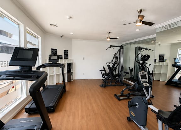 A gym with treadmills, weights, and exercise equipment.