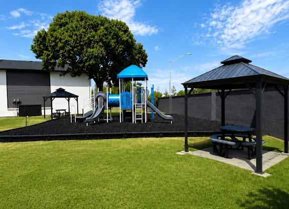 A playground with a blue slide and a black canopy.