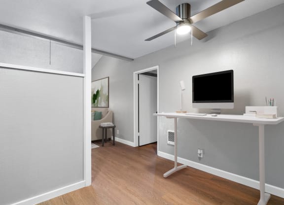 an open living room with a computer desk and a ceiling fan