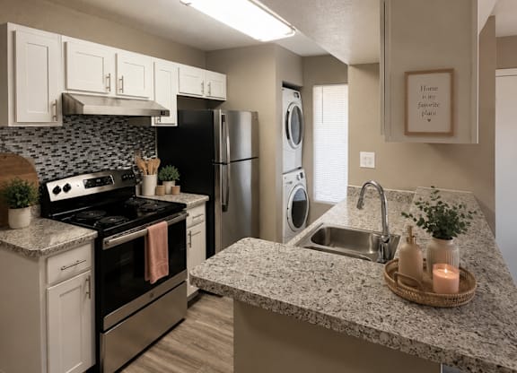 A kitchen with a stove, oven, refrigerator, and washing machine.