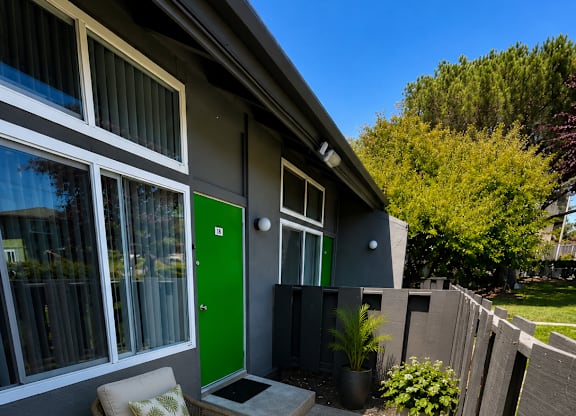 A small patio with a chair and table outside a house.