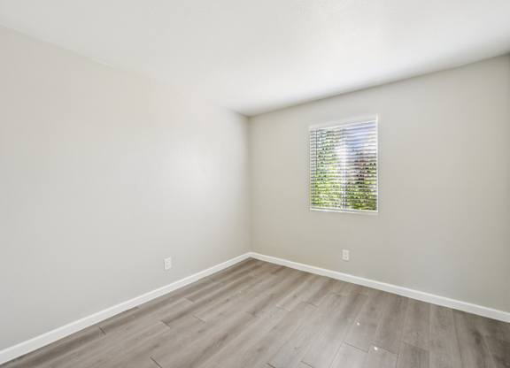 A room with a window and wooden flooring.