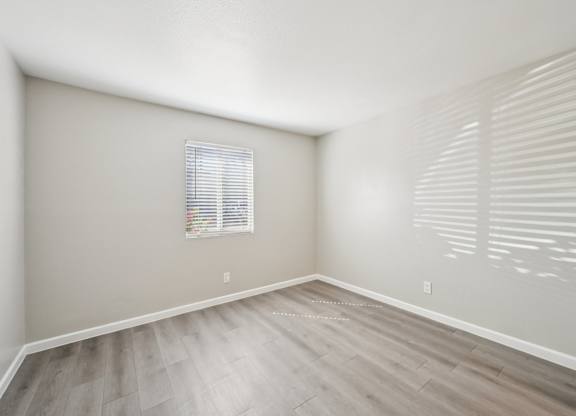 A room with a window and wooden flooring.