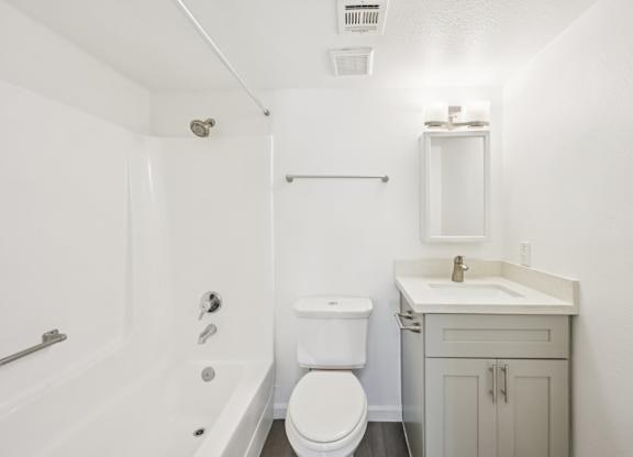 A white bathroom with a toilet, sink, and bathtub.