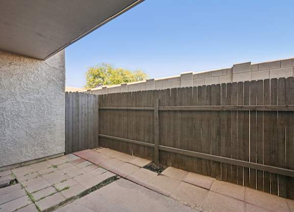 A concrete patio with a wooden fence and a wall.