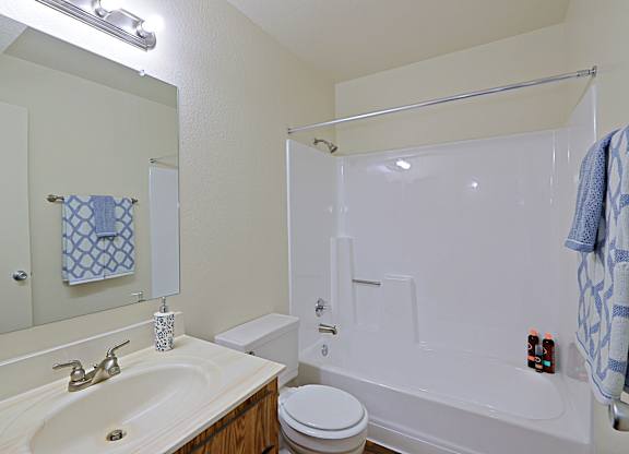 a bathroom with a white bathtub and a white sink with a mirror above it