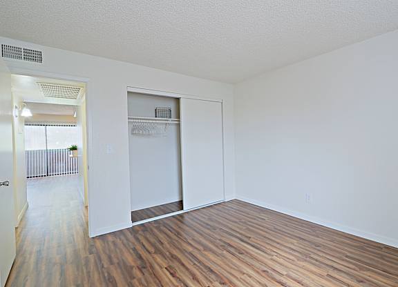 a bedroom with hardwood floors and white walls