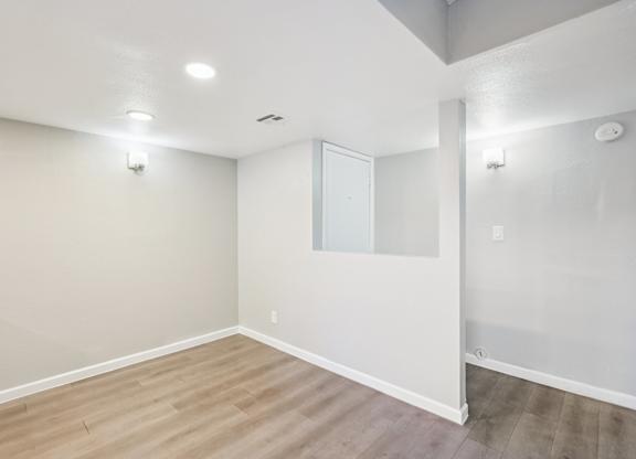 A room with a white wall and a wooden floor.