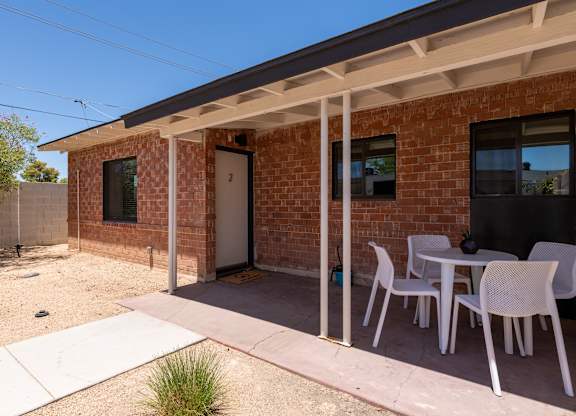 A patio with a table and chairs is outside a brick house.