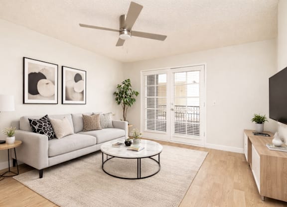 A living room with a grey couch, a coffee table, and a ceiling fan.