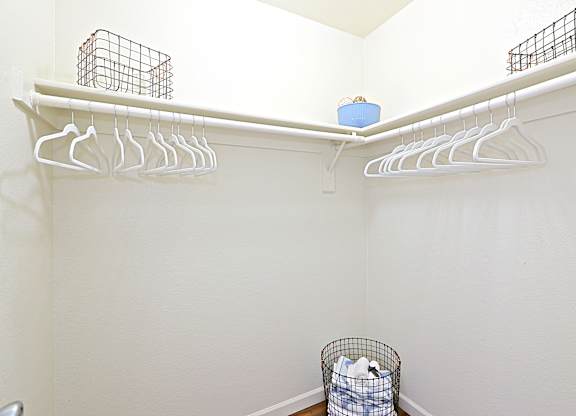 a walk in closet in a bathroom with white walls and a white rack with white hangers