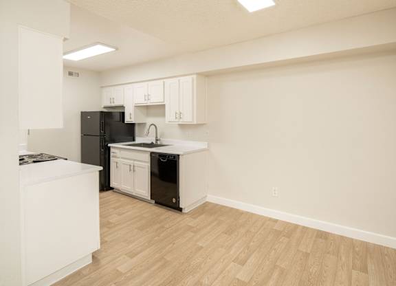 A kitchen with black appliances and white cabinets.