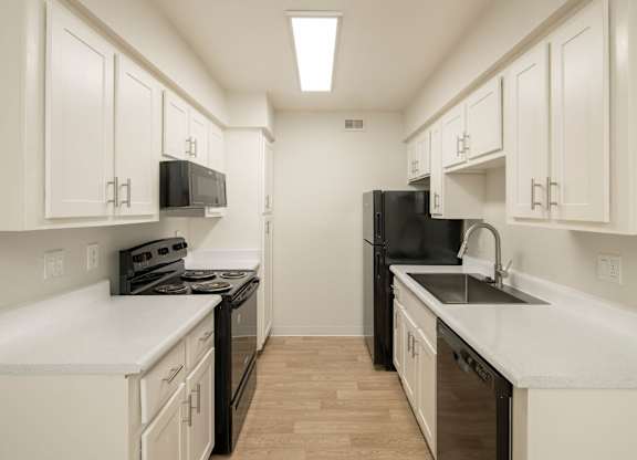 A kitchen with black appliances and white cabinets.