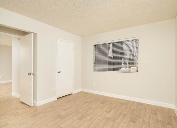 A room with a window and a wooden floor.