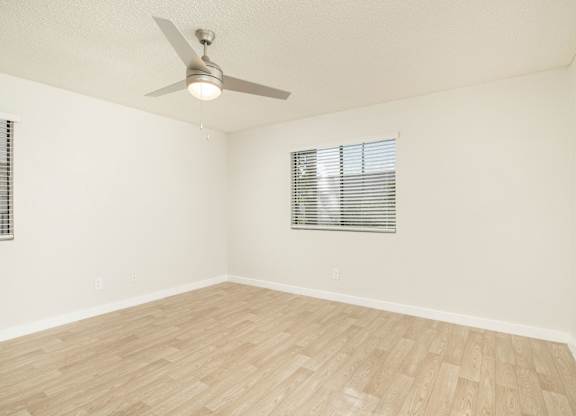 A room with a ceiling fan and wooden flooring.