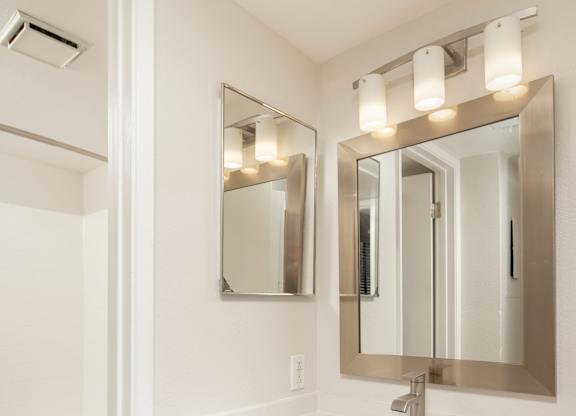 A white bathroom with a sink, mirror, and toilet.