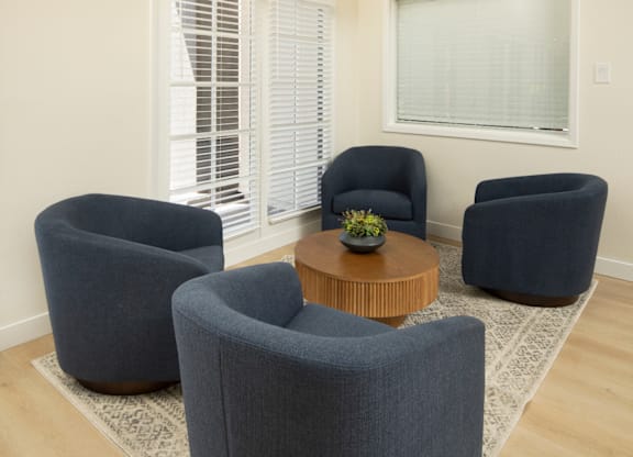 Three blue chairs are arranged around a wooden coffee table in a room.