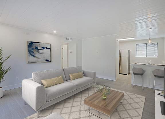 A living room with a grey couch and a painting on the wall.