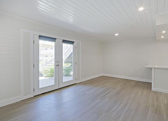 A room with a white ceiling and wooden flooring with a white cabinet and a window with blinds.
