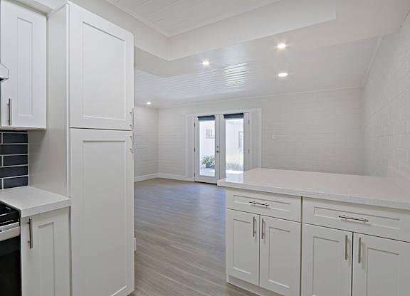 A kitchen with white cabinets and a window.