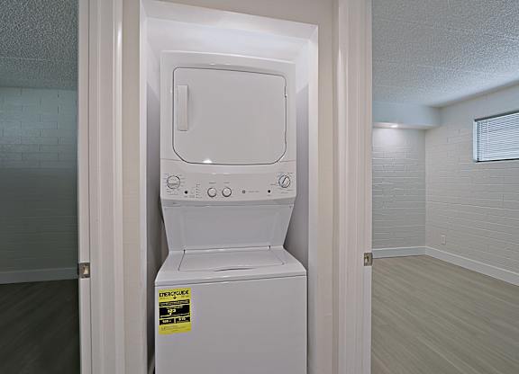 A white dryer is in a small room with a glass door.