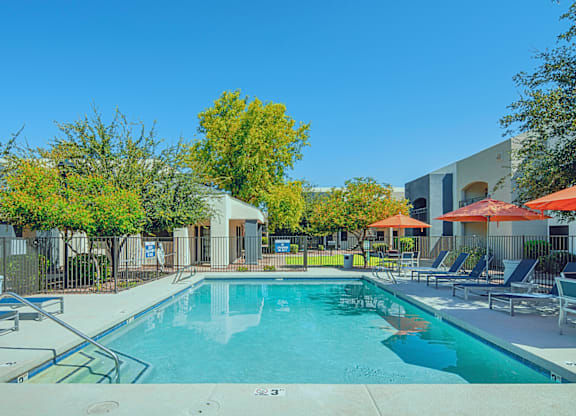 A swimming pool surrounded by trees and chairs.