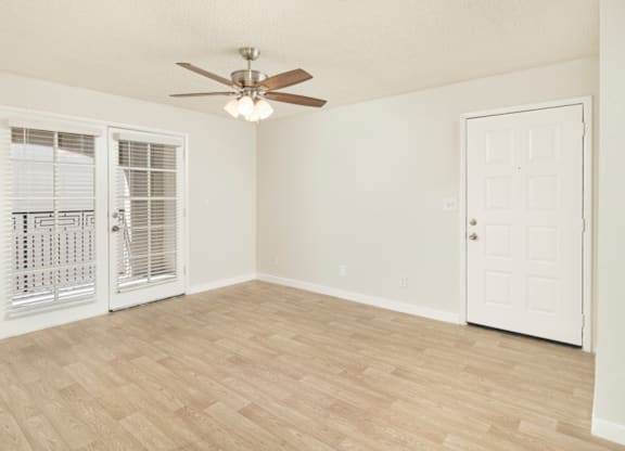 A room with a ceiling fan and a door.