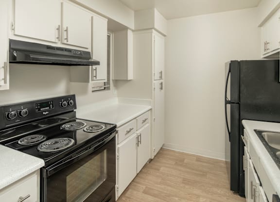 A kitchen with black appliances and white cabinets.