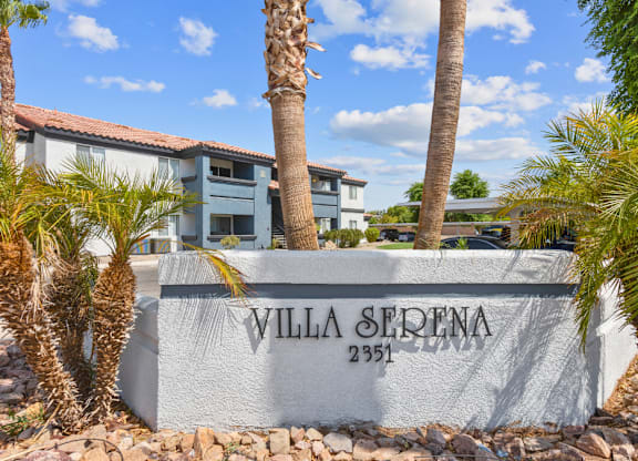 a wall with the villa sierra name on it and palm trees in front of it