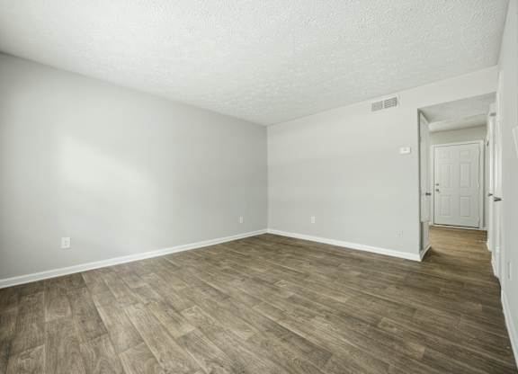 A room with wooden flooring and white walls.